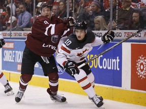 Canada's Kale Clague evades Latvia's Rihards Puide during their world junior hockey championships game in Toronto on Thursday Dec. 29, 2016.