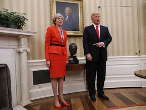 President Donald Trump points to the bust of British Prime Minister Winston Churchill as he poses for photographs with British Prime Minister Theresa May in the Oval Office of the White House in Washington, Friday, Jan. 27, 2017. (AP Photo/Pablo Martinez Monsivais)