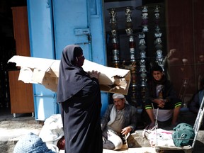 A Yemeni woman walks past street vendors at a secondhand market in the capital Sanaa, on January 14, 2017.