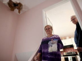 Theresa Couch, left  and her husband Richard look at the hole in the roof of their home in Calgary, Alta., on Saturday February 25, 2017, where a chunk of ice crashed through their roof from a passing plane.