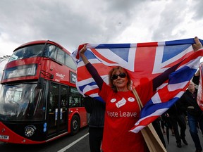 A campaigner wearing a Vote Leave t-shirt and holding a British Union Flag, also known as a Union Jack, stands on a Westminster Bridge near the Houses of Parliament in London, U.K., Wednesday, June 15, 2016. The Brexit battle took to London's River Thames as boats supporting the "Leave" and "Remain" campaigns jostled for space, while Irish rock star Bob Geldof harangued U.K. Independence Party leader Nigel Farage using a sound system.