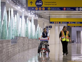 Employees walk through the arrivals level of the new international terminal of the Calgary International Airport in Calgary, Alta., on Monday, Oct. 31, 2016. The $2 billion facility was in its opening day.