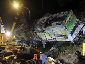 A bus that crashed along a highway is lifted by cranes in Taipei on February 14, 2017.