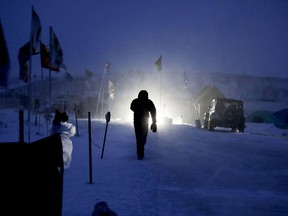 A camper walks through the Oceti Sakowin camp where people have gathered to protest the Dakota Access oil pipeline in Cannon Ball, N.D., Tuesday, Dec. 6, 2016. An overnight storm brought several inches of snow, winds gusting to 50 mph and temperatures that felt as cold as 10 degrees below zero.
