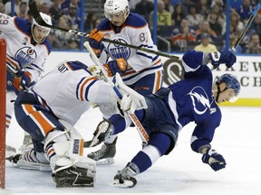 Edmonton Oilers defenseman Matt Benning takes down Tampa Bay Lightning left wing Ondrej Palat in front of goalie Laurent Brossoit during the second period Tuesday in Tampa, Fla.