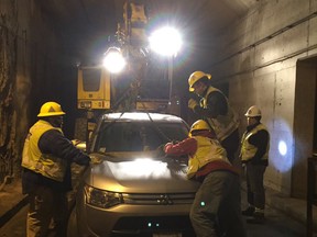 TTC workers use a crane to remove a car that got stuck in a streetcar tunnel in Toronto.