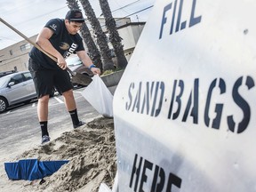 Chad Adriano fills up sand bags before the weekend storms at the Orange County Fire Authority Station 44 in downtown in Seal Beach, Calif.