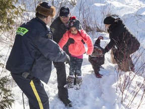 Family members from Somalia are helped into Canada by RCMP officers along the U.S.-Canada border near Hemmingford, Que., on Friday, Feb. 17, 2017.