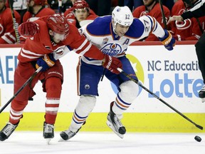Brett Pesce, left, of the Carolina Hurricanes applies a hook in an attempt to impede the progress of Milan Lucic of the Edmonton Oilers during NHL action Friday night in Raleigh, N.C. The Hurricanes won the game 2-1, handing the Oilers their third straight defeat since coming back from the All-Streak break.