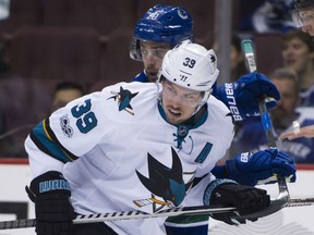 Brandon Sutter of the Canucks is tied up by the San Jose Sharks' Logan Couture during the first period of their game at Rogers Arena in Vancouver on Saturday night.