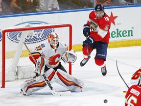 Calgary Flames' goaltender Chad Johnson follows a bouncing puck in front of his goal during NHL action Friday night in Sunrise, Fla. To Johnson's left is Reilly Smith of the Florida Panthers. Johnson had 36 saves as the Flames made it three straight wins on the road with a 4-2 decision.