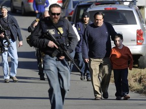 In this Friday, Dec. 14, 2012 file photo, parents leave a staging area after being reunited with their children following a shooting at the Sandy Hook Elementary School in Newtown, Conn., where Adam Lanza fatally shot 27 people, including 20 children.