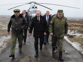 Vladimir Putin (front C) and Defence Minister Sergei Shoigu (front L)  walk to watch military exercises upon his arrival at the Kirillovsky firing ground in the Leningrad region, on March 3, 2014.
