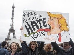 People hold a banner reading "Make America hate again" during a gathering to protest U.S. President Donald Trump's recent travel ban to the U.S. at Trocadero Plaza next to the Eiffel Tower in Paris, Saturday, Feb. 4, 2017.