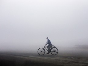 A man cycles through the smog on National Highway 1 in Karnal, Haryana, India, on Tuesday, Dec. 8, 2015.