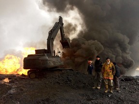 Employees from Iraq's North Oil Co. monitor firefighters trying to control a oil fire at well 77 near Qayyarah, Iraq. Authorities say the well burns between 500 and 1,000 barrels of oil each day.