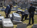 Police dust for fingerprints on one of the more than 100 headstones that were knocked down at Mount Carmel Cemetery in Philadelphia on Sunday, Feb. 26, 2017.