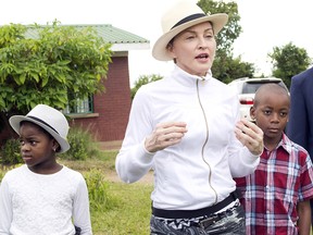 In this Friday, April 5, 2013 file photo Madonna, center, tours the Mphandura orpahange near Lilongwe, Malawi with her two adopted children David Banda, right and Mercy James, left. Court documents in Malawi say Madonna was asked "uncomfortable questions" by a judge during the pop star's successful application to adopt twins from the country in southern Africa Tuesday, Feb. 7 2017.
