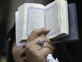 An Iranian protestor holds a copy of the Quran on Thursday, Sept. 13, 2012