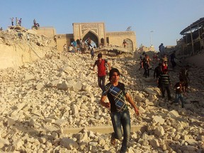 People walk on the rubble of the destroyed Nebi Yunus shrine in Mosul, Iraq, on July 24, 2014, after it was blown up by ISIL extremists.