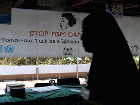 A young woman walks past a campaign banner against female genital mutilation