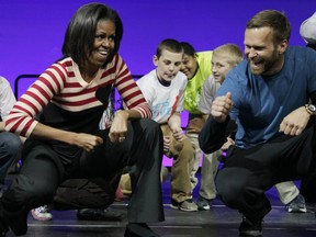 In this Feb. 9, 2012, file photo, first lady Michelle Obama and Bob Harper of "The Biggest Loser," right in blue shirt, do the Interlude dance during a Let's Move event with children from Iowa schools at the Wells Fargo Arena in Des Moines, Iowa