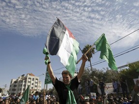 In this Tuesday, Oct. 18, 2011 file photo, a Hamas militant waves a green Islamic flag and a Palestinian flag to the crowd after arriving in the West Bank city of Ramallah