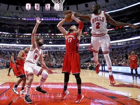 Jerian Grant of the Bulls blocks the shot of Toronto Raptors' Jonas Valanciunas as Robin Lopez looks on during the second half of their game Tuesday night in Chicago. The Bulls won 105-94.