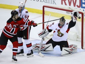 Joseph Blandisi of the Devils tries to deflect a shot as Ottawa Senators goalie Craig Anderson and defenceman Erik Karlsson protect their net during the third period on Tuesday night in Newark, N.J. The Senators won 2-1.