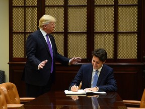 U.S. President Donald Trump accompanies Prime Minister Justin Trudeau as he signs the guest book in the Roosevelt Room of the White House, in Washington, D.C., on Monday, Feb. 13, 2017.