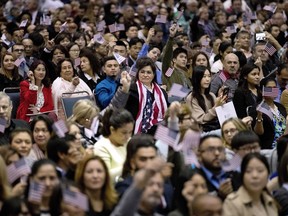 People wave U.S. flags during a naturalization ceremony at the Los Angeles Convention Center, in Los Angeles.