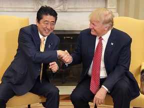 U.S. President Donald Trump, right, shakes hands with Shinzo Abe, Japan's prime minter, while posing for photographs before a joint news conference in the Oval Office of the White House in Washington, D.C., U.S., on Friday, Feb. 10, 2017. Japan and the U.S. will begin new talks on trade and investment following President Donald Trumps decision to withdraw from the Trans-Pacific Partnership, the two governments said in a statement after their leaders met in Washington on Friday.