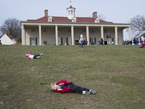 Four-year-old Sam Merrill and his two-year-old sister Martha Merrill do log rolls down the hill at Mount Vernon, which marked George Washington's 285th birthday Wednesday with free admission and unseasonable temperatures.