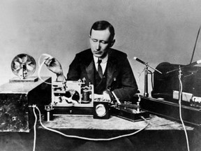 Guglielmo Marconi demonstrating apparatus he used in his first long distance radio transmissions in the 1890s. The transmitter is at right, the receiver with paper tape recorder at left.