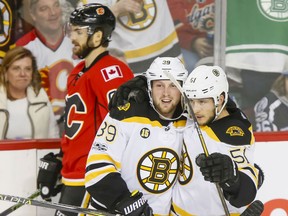 Matt Beleskey and Ryan Spooner of the Boston Bruins celebrate a third-period goal as Michael Frolik of the Flames skates by during their game in Calgary, on Wednesday night. Boston won 5-2, snapping a 10-game Flames winning streak.