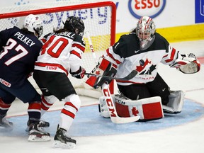 Shannon Szabados of Canada keeps her eye on the puck next to teammate Blayre Turnbull and Amanda Pelkey of the United States at the women's world hockey championship in Plymouth, Mich., on Friday night.