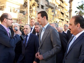 A handout picture released by the official Syrian Arab News Agency (SANA) on September 12, 2016, shows Syrian President Bashar al-Assad (C) speaking with the press as he walks in the street alongside officials after performing the morning Eid al-Adha prayer at a mosque in a government-controlled area of Daraya.