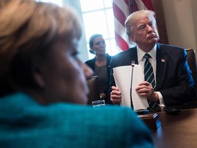 Germany's Chancellor Angela Merkel (L) and US President Donald Trump listen as participants introduce themselves before a meeting with Germans and US business leaders in the Cabinet Room of the White House March 17, 2017 in Washington, DC.