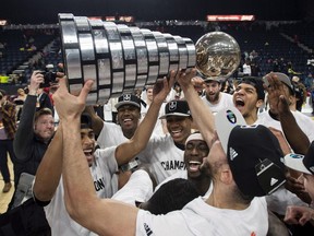 Members of the Carleton Ravens men's basketball team raise the W.P McGee Trophy following their win over the Ryerson Rams in the USports basketball national championship game in Halifax on March 12.
