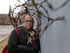 In this Tuesday, Feb. 21, 2017, photo, Pastor Corey Brooks of the New Beginnings Church poses for a portrait on a under maintained security wall that hugs the sprawling Norfolk Southern train yard and his church on Chicago's South Side.