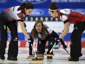 Rachel Homan of Canada, centre, shouts as her teammates Joanne Courtney, right, and Lisa Weagle sweep the path for the stone during a match against Russia at the women's world curling championships in Beijing on March 19.
