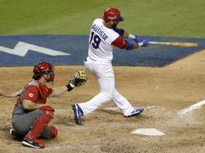 Jose Bautista of defending champion Dominican Republic follows through on his three-run homerun against Canada in World Baseball Classic action Thursday in Miami. Catcher is George Kottaras. Bautista had three hits and four RBI as the Domincan Republic posted a 9-2 victory.