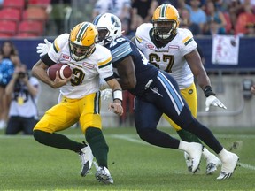 Toronto Argonauts defensive end Shawn Lemon (centre) pursues Edmonton Eskimos quarterback Mike Reilly (left) on Aug. 20, 2016.