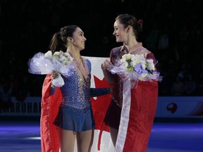 Kaetlyn Osmond, right, and Gabrielle Daleman, both of Canada, smile posing with their silver and bronze medals and the national flag during victory ceremony at the world figure skating championships in Helsinki on March 31.