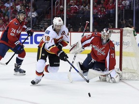 Calgary Flames' Troy Brouwer moves the puck in front of Capitals defenseman John Carlson and goalie Braden Holtby during the first period of their game Tuesday night in Washington.
