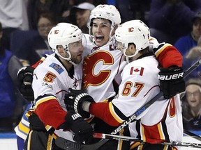 Sean Monahan, centre, is congratulated by Calgary Flames teammates Mark Giordano, left, and Michael Frolik, after scoring the game-winning goal during overtime against the Blues in St. Louis on Saturday night.