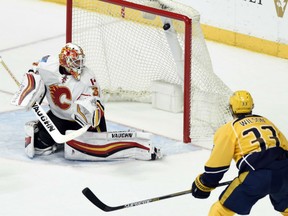 Goaltender Chad Johnson of the Calgary Flames looks over his shoulder as a shot finds the upper portion of the net during NHL action Thursday night in Nashville. Looking on is Colin Wilson of the Preds. Nashville won the game 3-1.