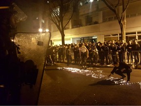 Youths use candles to write the word "Violence" in the road in front of a line of riot police in 19th Arrondissement (District) of Paris late on March 27, 2017.