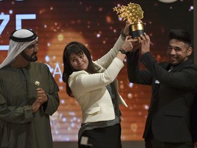 Maggie MacDonnell raises the Global Teacher Prize with one of her students while standing next to Dubai ruler Sheikh Mohammed bin Rashid Al Maktoum, in Dubai, United Arab Emirates, Sunday, March 19, 2017.