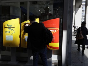 A man drops an envelope in a box at the central post office in Athens, Tuesday, March 21, 2017. Police in Greece have discovered and neutralized eight parcel bombs on Monday, addressed to European Union finance officials and businesses in various European countries, at a postal sorting office near Athens.